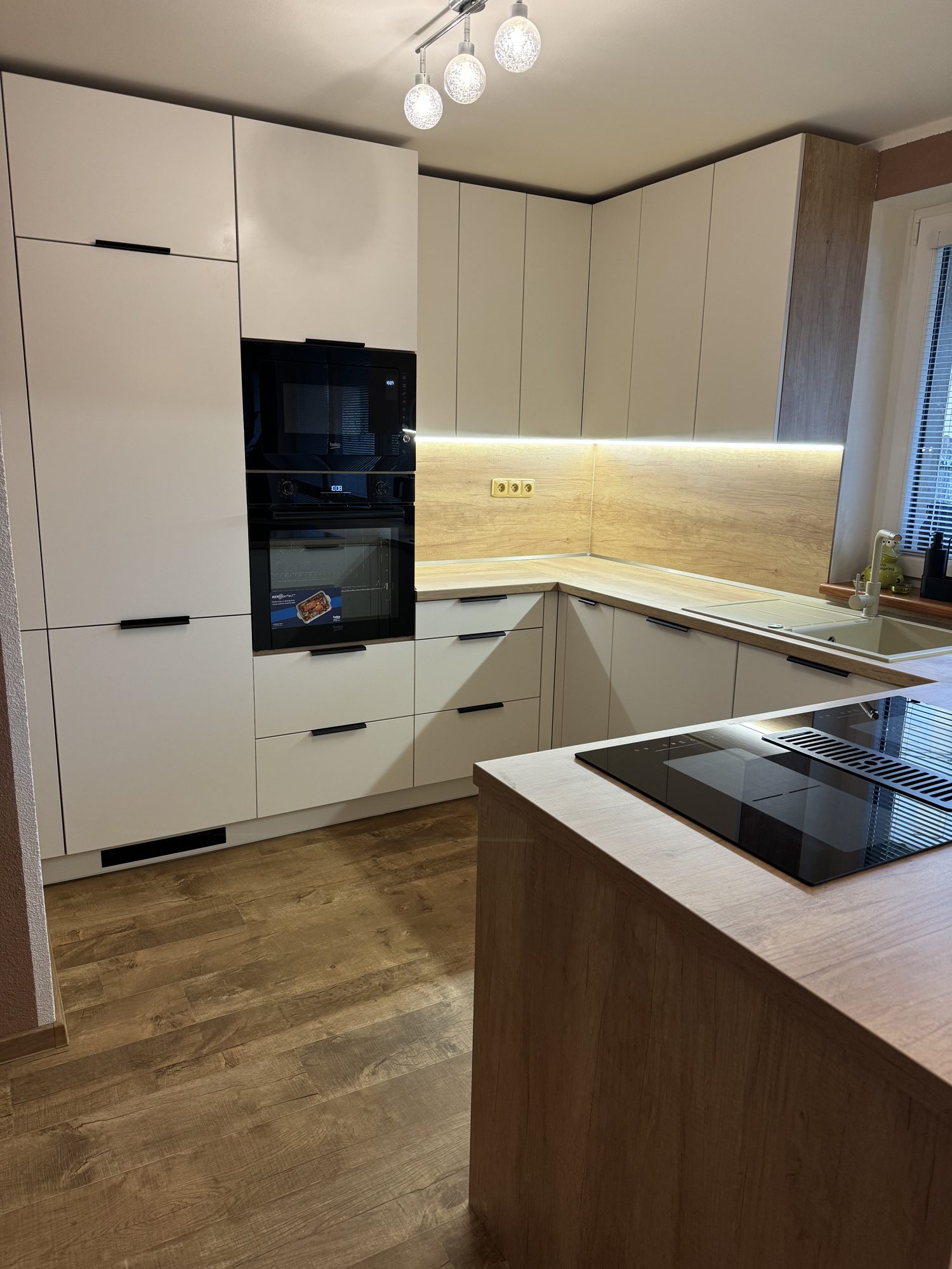 Realizace LS Kuchyně — bílá kuchyně do U s poloostrovem, indukční deskou s odsáváním a LED podsvícením